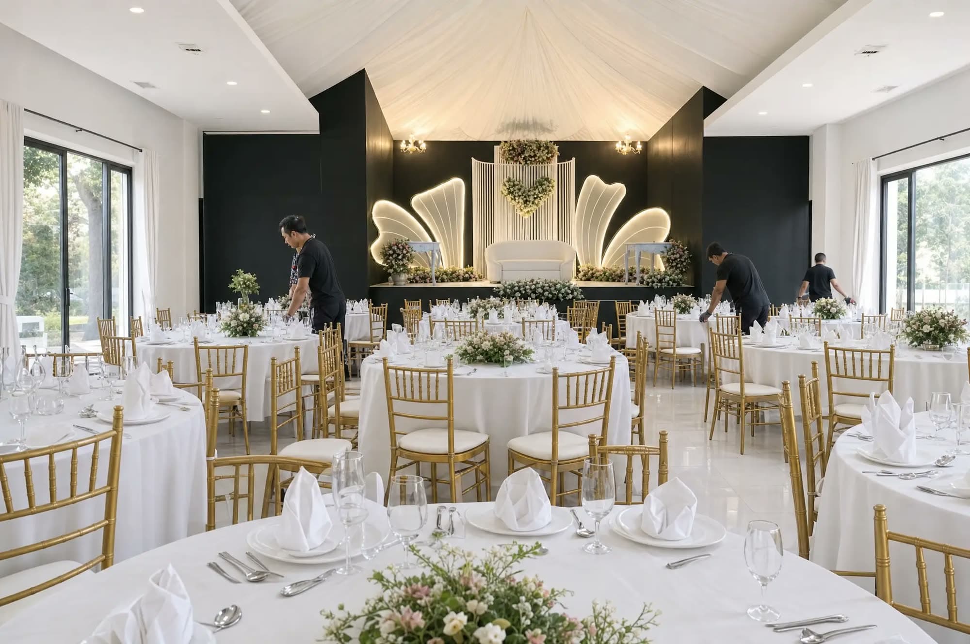 Event hall mid-setup in daylight with tables being laid with white linen